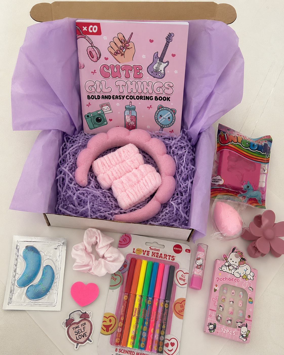 Girls birthday surprise box open showing colourful contents including colouring book, fluffy headband, scented markers, press-on nails and beauty accessories