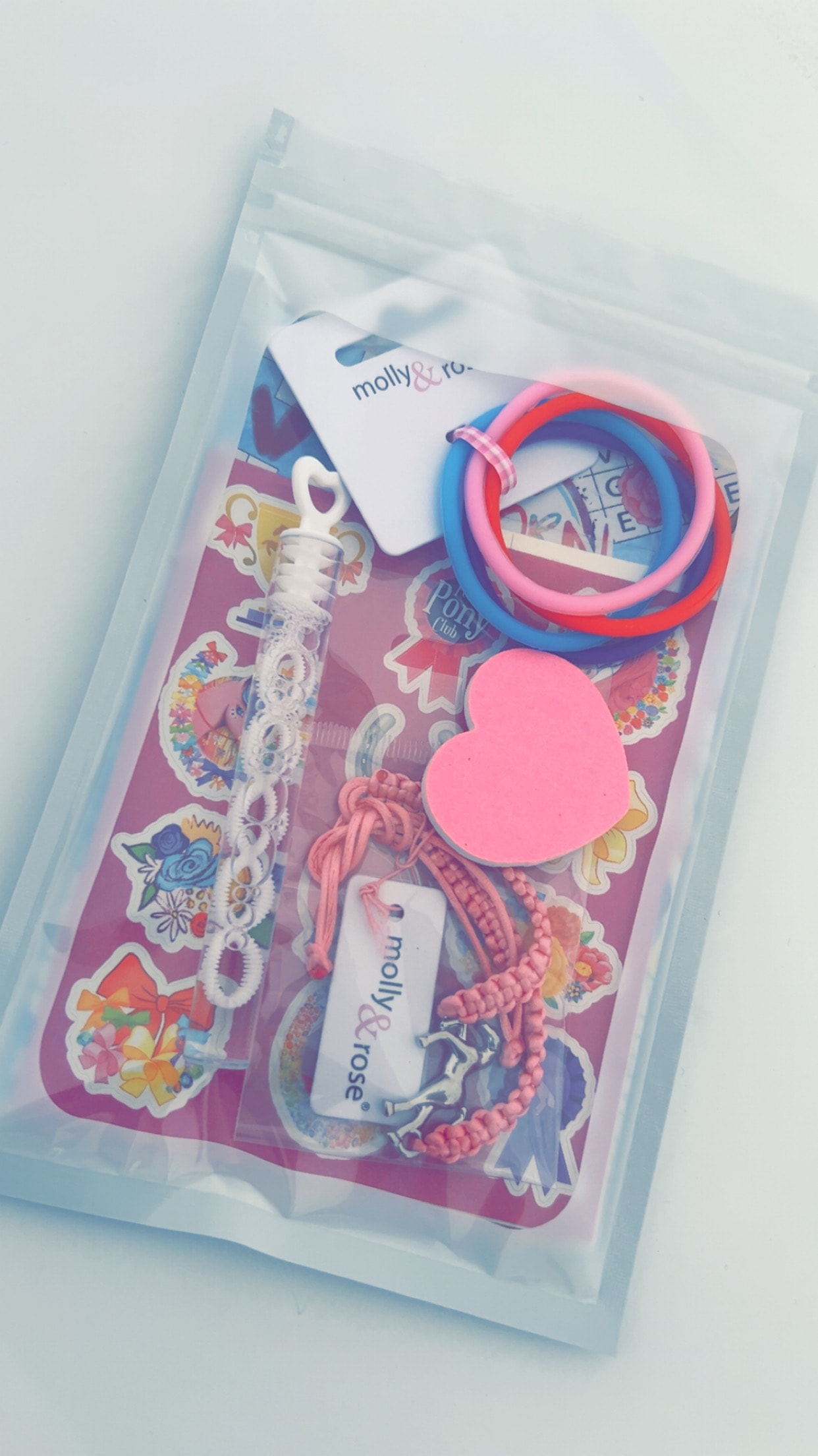 Unicorn themed party bag contents including colourful hair ties, bracelets, stickers and a heart keepsake