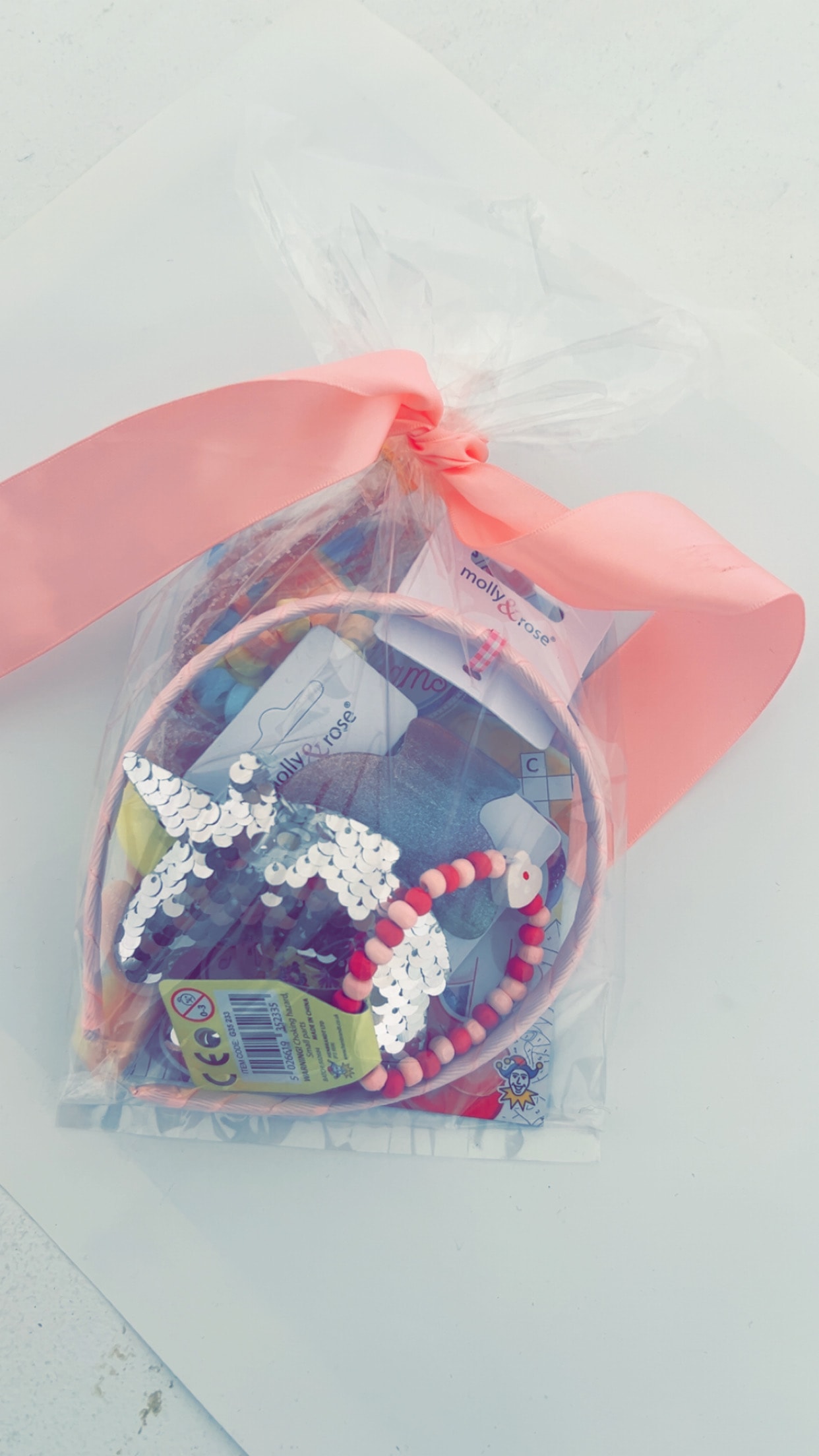 Girls' unicorn party bag filled with accessories, stationery and sweet treats tied with a pink ribbon
